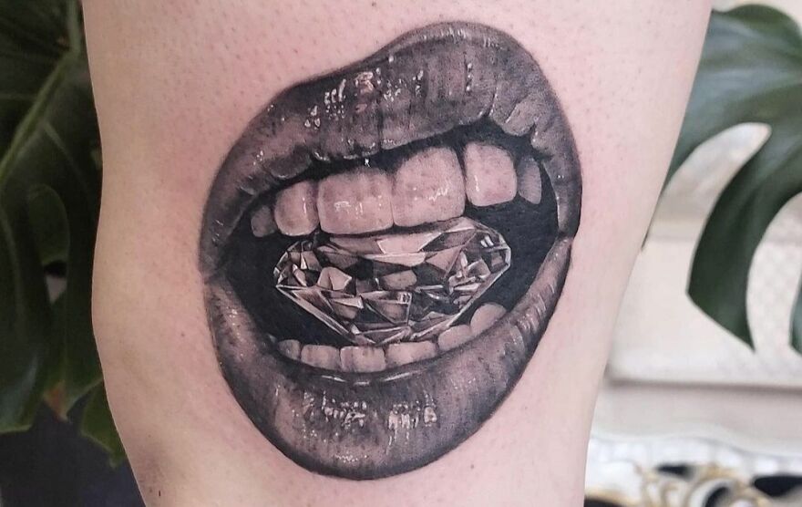 Realistic tattoo of lips holding a diamond, showcasing flawless artistry suitable for a museum.