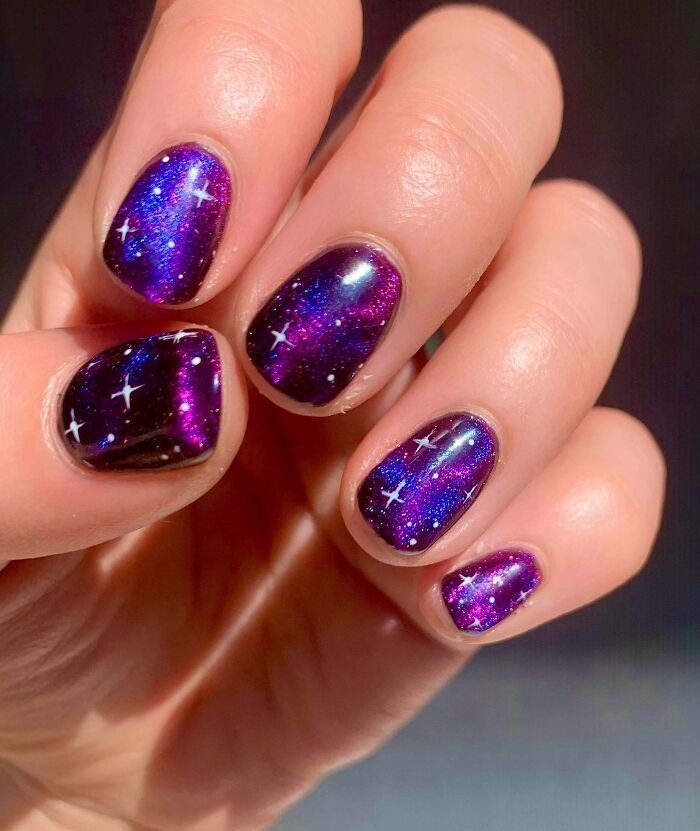Galaxy-themed nail art design with a purple and black gradient, featuring stars, showcasing a creative nail art idea.