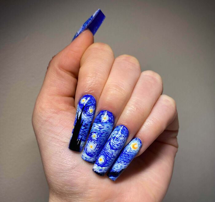 Hand displaying blue and yellow nail art inspired by Starry Night, showcasing creative nail art ideas.