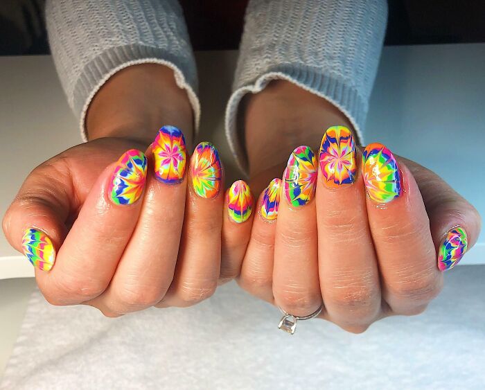 Colorful nail art featuring intricate, vibrant designs on manicured hands, perfect for your next appointment.