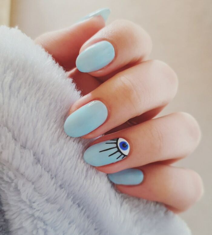 Light blue nail art with an eye design on a single nail for creative manicure ideas.