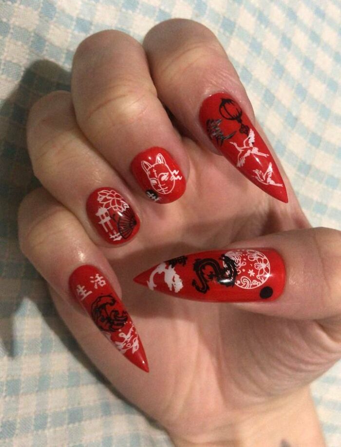 Red nail art with intricate designs, including cats and cranes, showcasing a unique nail art idea.