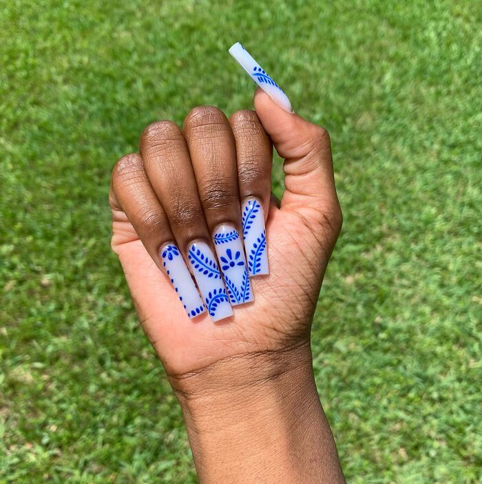 Creative nail art with blue patterns on white nails, perfect for your next appointment.