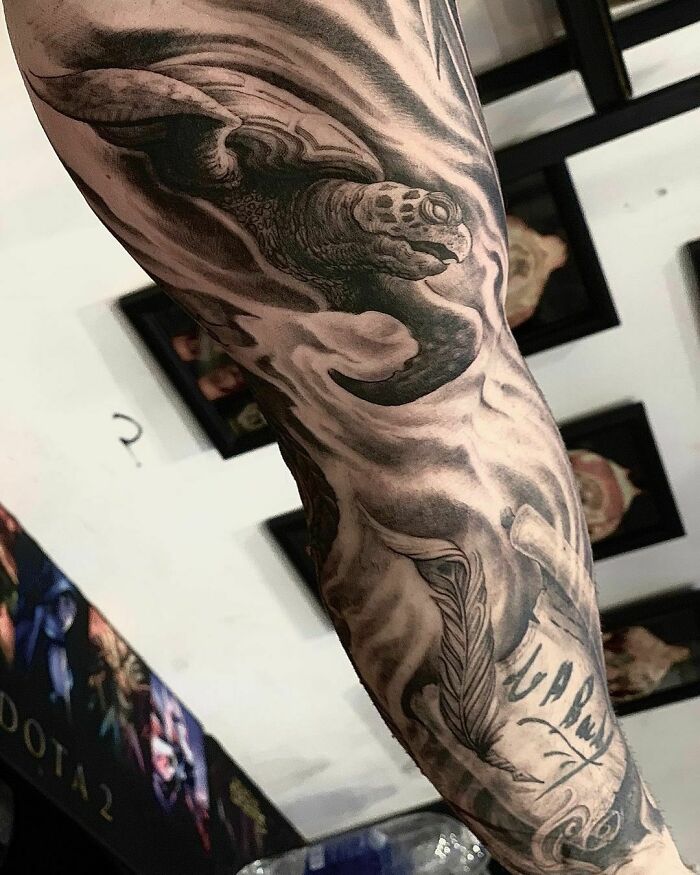 Realistic tattoo of a sea turtle and feather, showcasing intricate details on an arm.