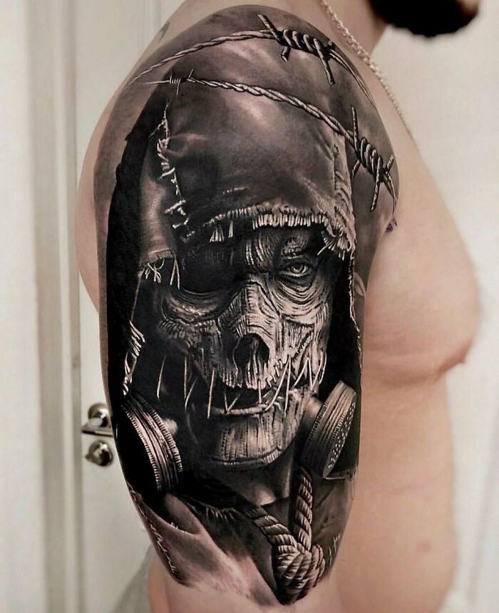 Super realistic tattoo of a hooded skull with barbed wire and ropes on a person's upper arm.