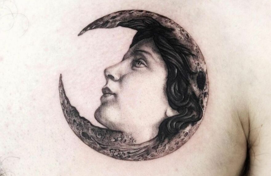 Realistic tattoo of a face within a crescent moon on skin, showcasing exquisite detail and artistry.