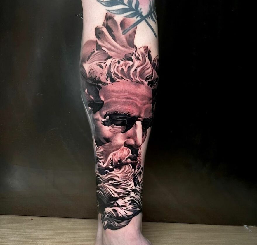 Realistic tattoo of a sculpted face on a person's calf, showcasing intricate details and lifelike shading.