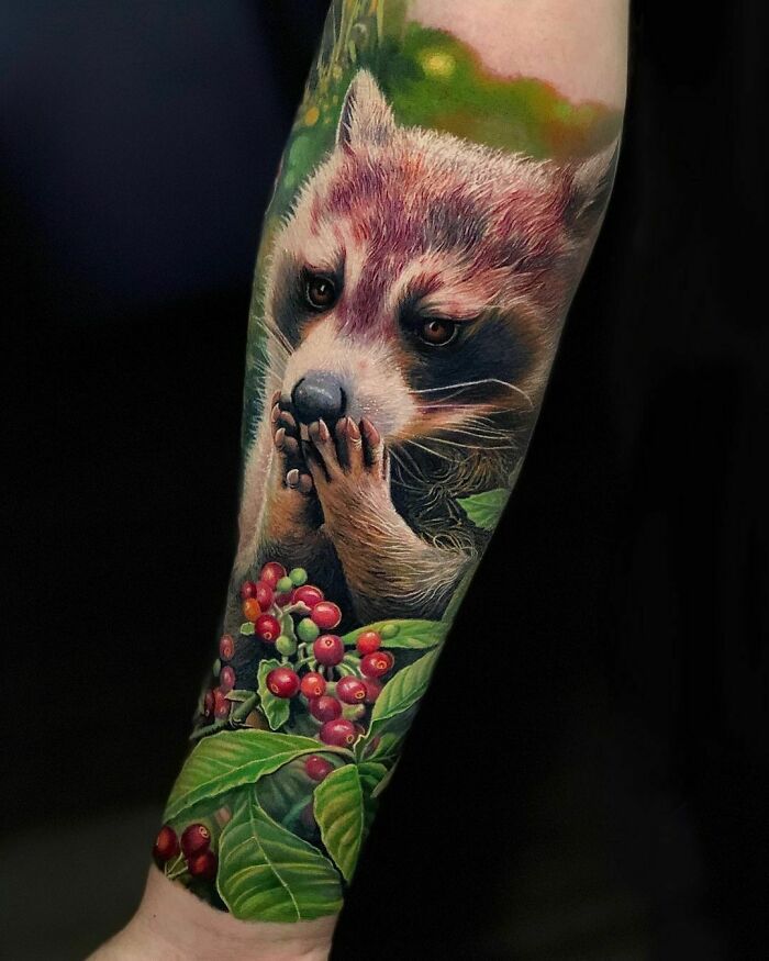 Realistic tattoo of a raccoon with berries on an arm, featuring vibrant colors and detailed design.