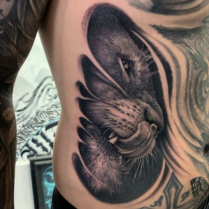 Realistic tattoo of a lion on a person's side, showcasing intricate detail and shading.