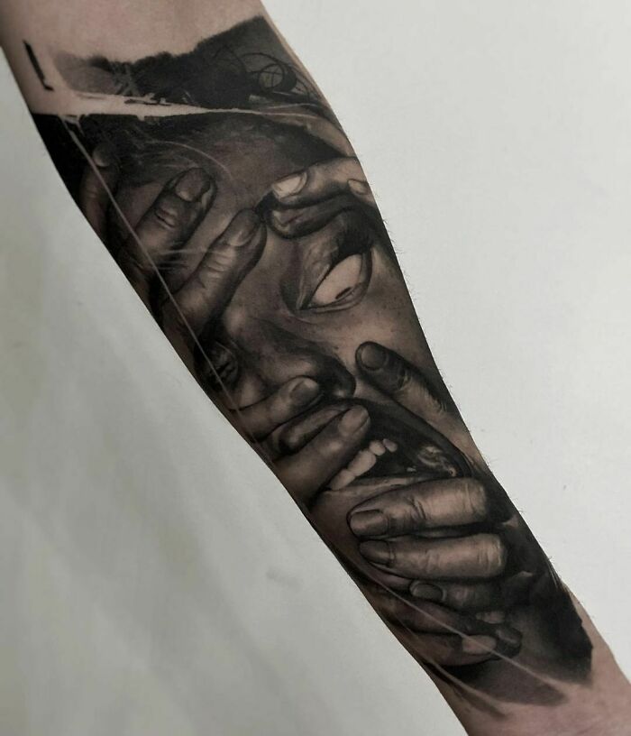Realistic tattoo of hands covering a face, showcasing intricate detail on a forearm.