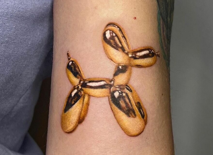 Golden balloon dog tattoo showcasing super realistic detailing.
