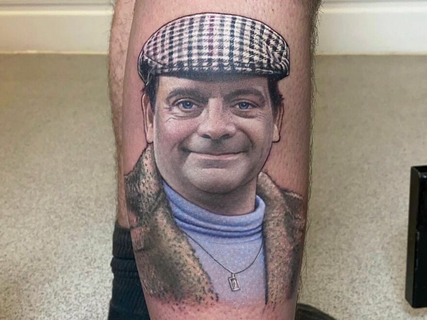 Realistic tattoo of a smiling man in a cap and coat on a person's leg.
