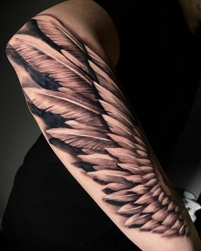 Realistic tattoo of detailed feathers on a person's arm, showcasing impressive artistry and skill.