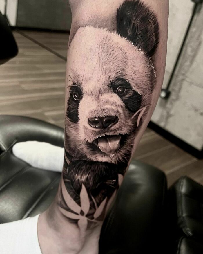 Realistic tattoo of a panda on an arm, showcasing detailed artwork and lifelike shading.