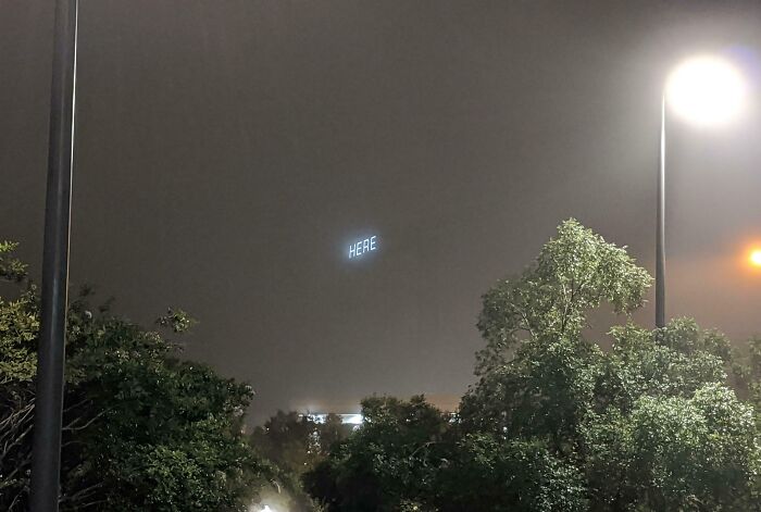 A Crane Outside Of My Work On A Foggy Morning With The Word Here Illuminated