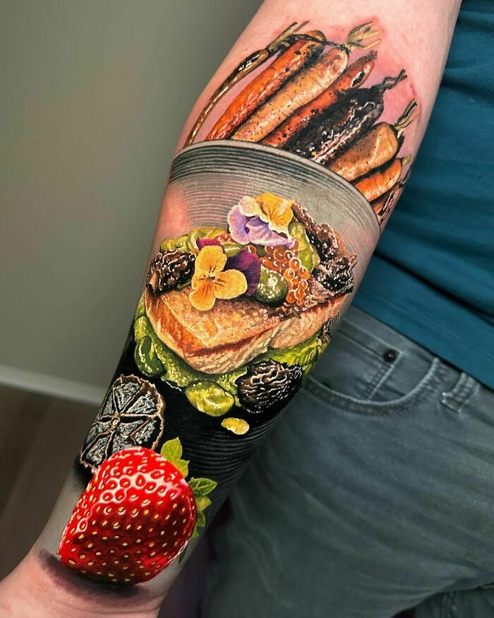 Realistic tattoo on a forearm depicting a vibrant, detailed dish with a strawberry, resembling a museum-worthy artwork.