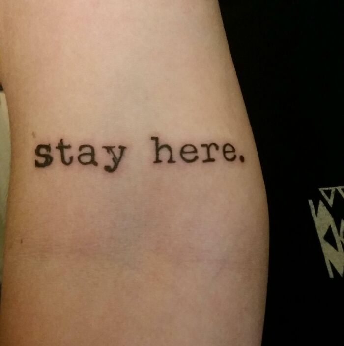 Tattoo on arm with the words "stay here."