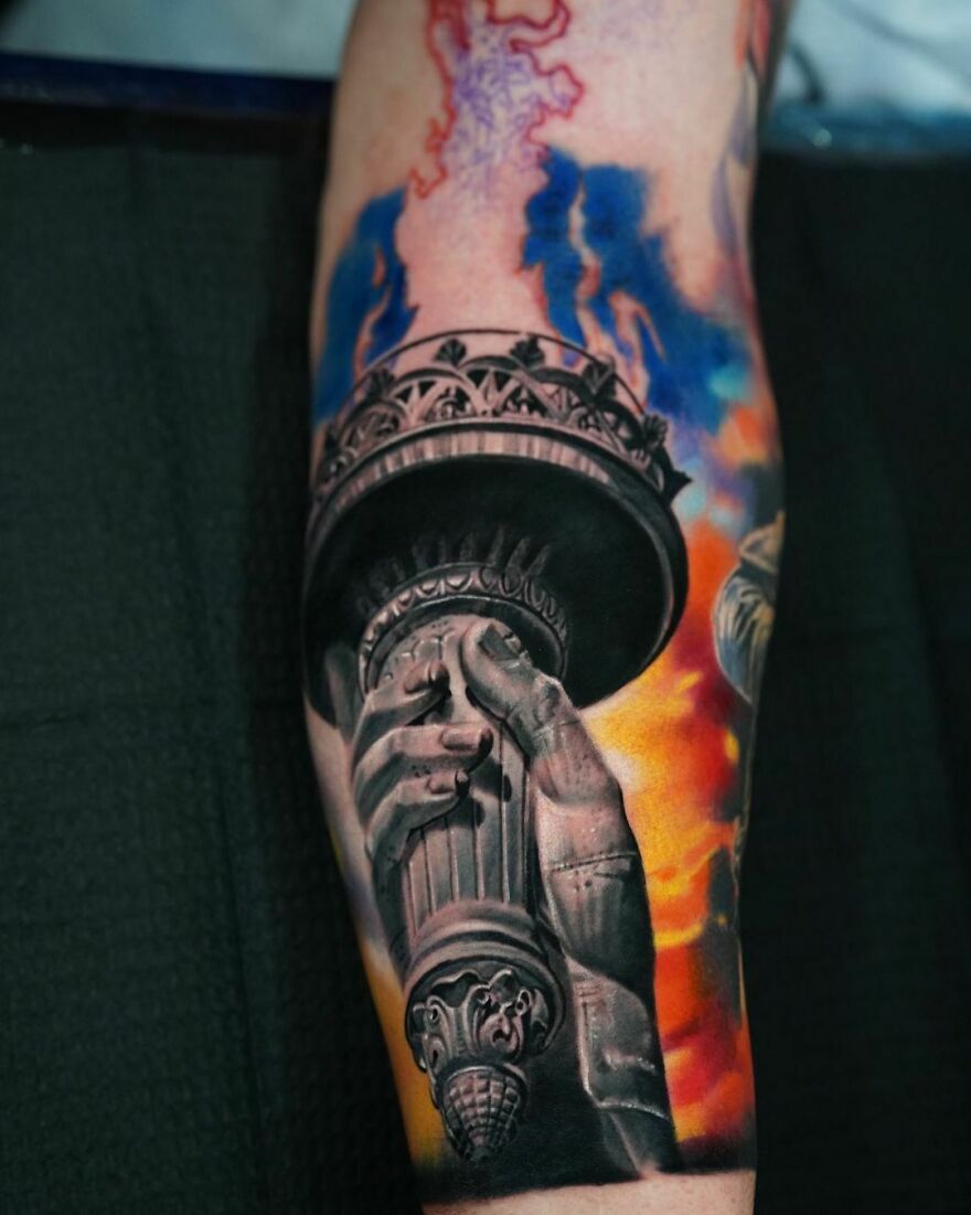 Super realistic hand holding torch tattoo with intricate detailing and vibrant colors on forearm.