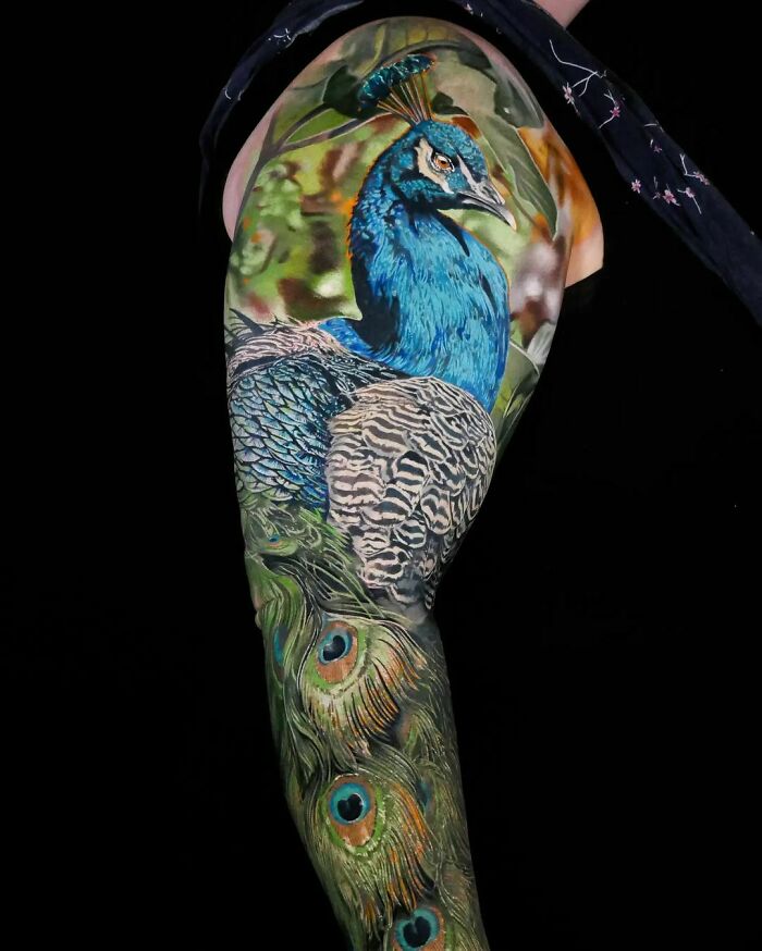 Realistic tattoo of a vibrant peacock on an arm, showcasing intricate detail and lifelike colors.