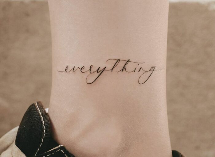 Word tattoos on wrist displaying the word "everything" in elegant script.