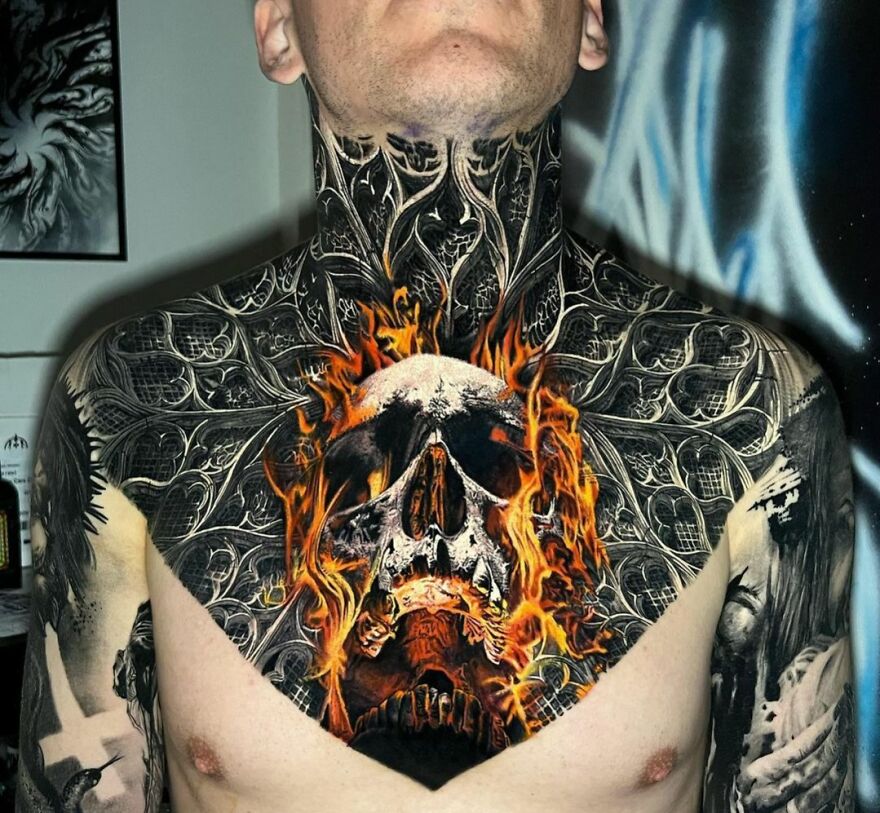 Realistic tattoo of a flaming skull on a person's chest and neck, showcasing intricate and detailed design.