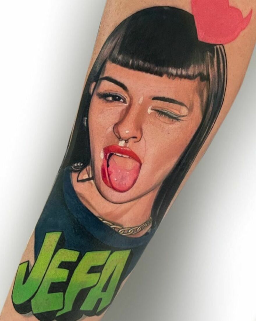 Cheeky woman's portrait tattoo showcasing super realistic detailing with bright red lips and winking eye.
