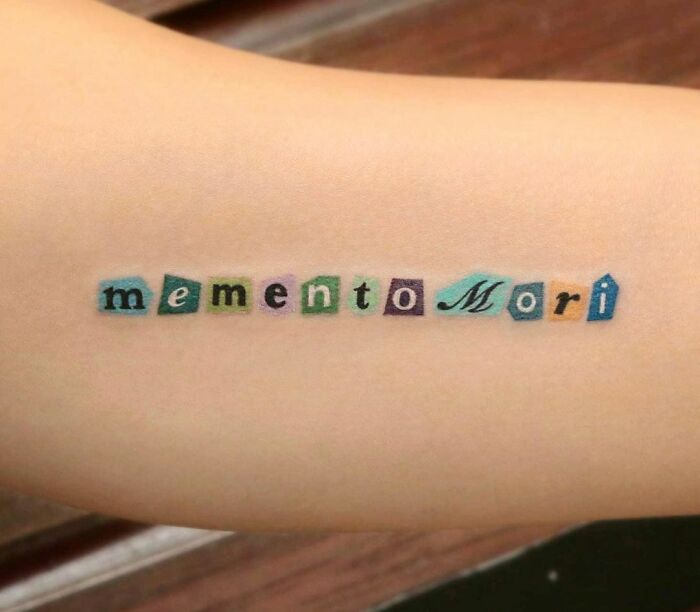 Colorful "memento mori" tattoo on arm showcasing creative word tattoos.