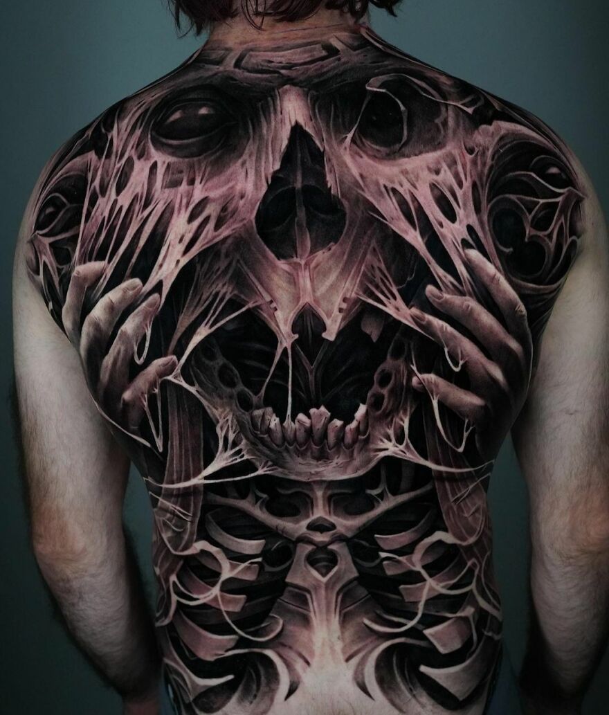 Super realistic back tattoo of a dark face ripping through skin, showcasing intricate detail.
