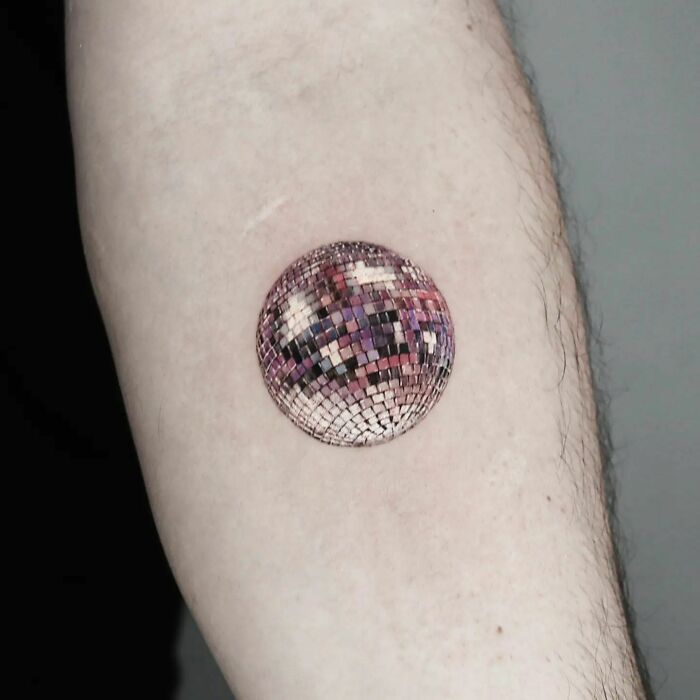 Realistic tattoo of a disco ball on skin, showcasing intricate detail and museum-worthy artistry.