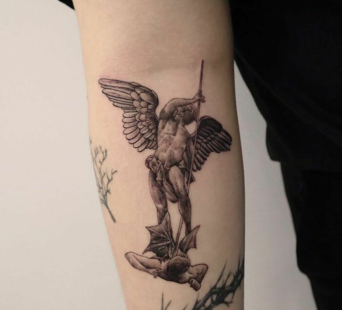 Realistic tattoo of an angel battling a demon on an arm, showcasing intricate detail.