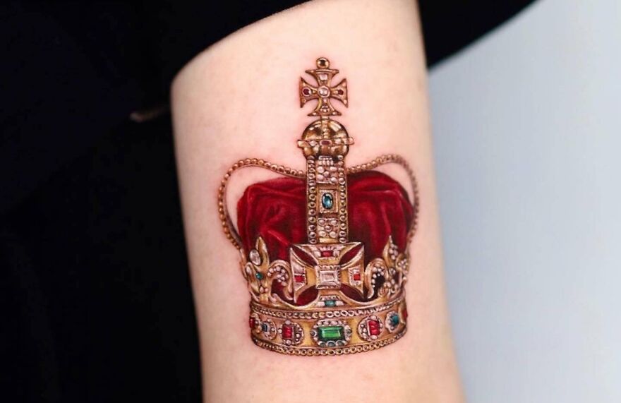 Realistic tattoo of an ornate crown with jewels on skin.