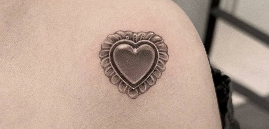 Realistic heart-shaped tattoo with intricate details on the upper arm.