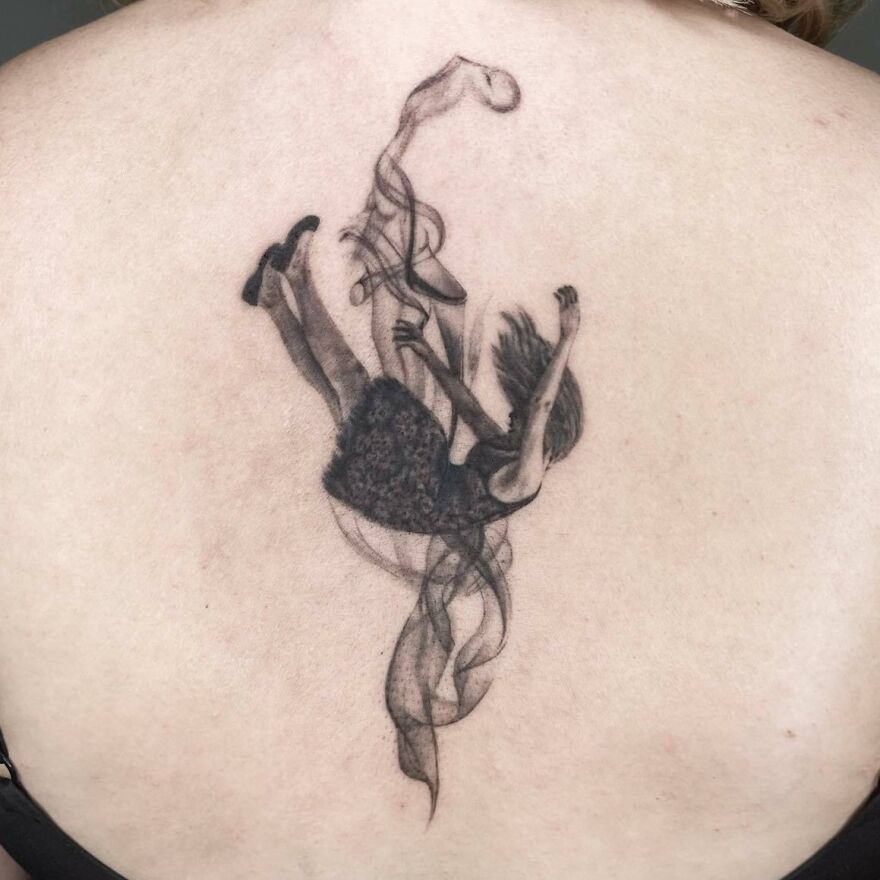 Realistic tattoo of a person falling, with intricate details, on a person's back.