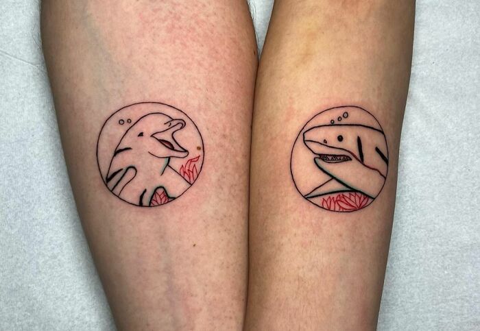 Matching tattoos of cartoon dolphins inside circles, symbolizing special relationships.
