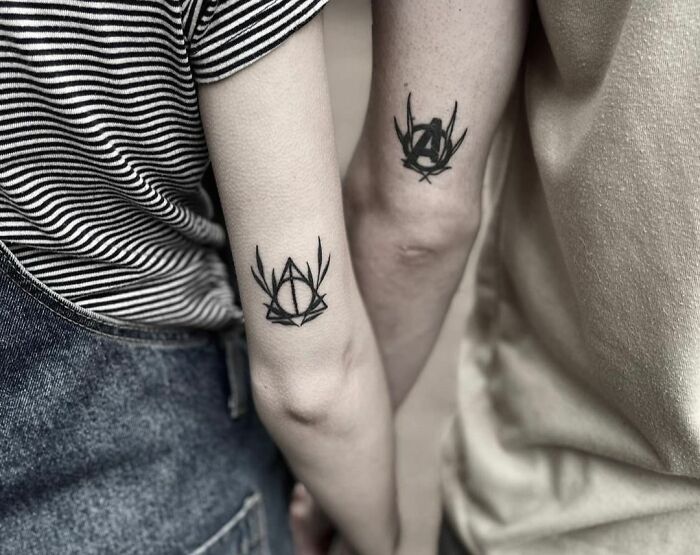 Matching tattoos on a couple's arms featuring geometric designs, symbolizing a special bond.