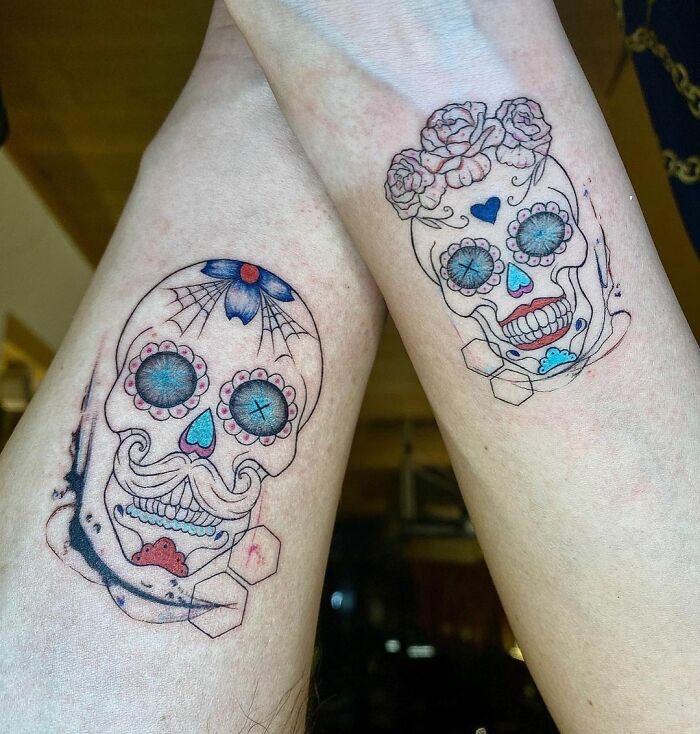 Sugar skull matching tattoos on forearms for couples or friends, featuring colorful floral designs and intricate details.