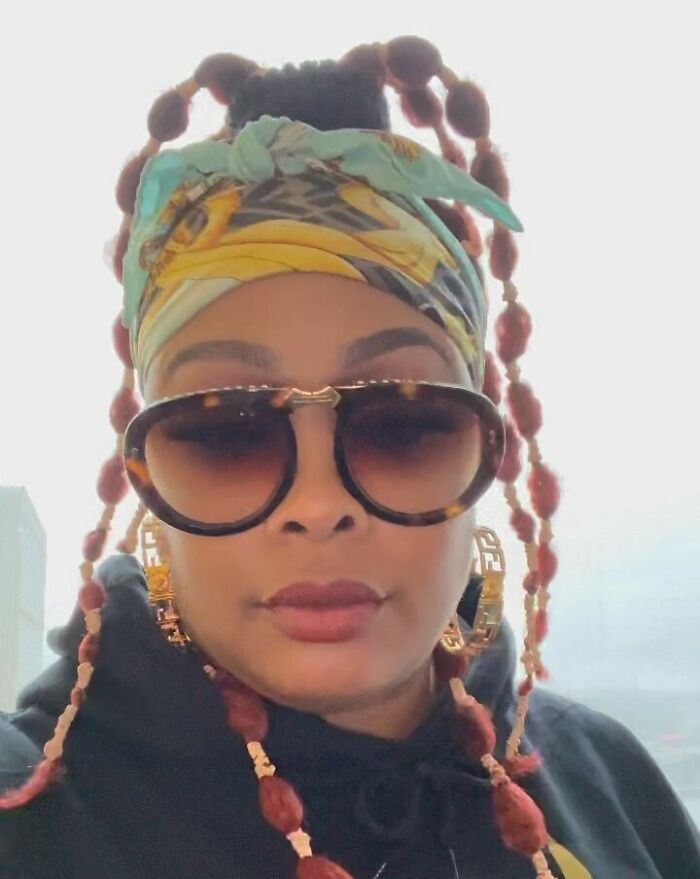 Celebrity in sunglasses and colorful headscarf, linked to jail history for minor and severe crimes.