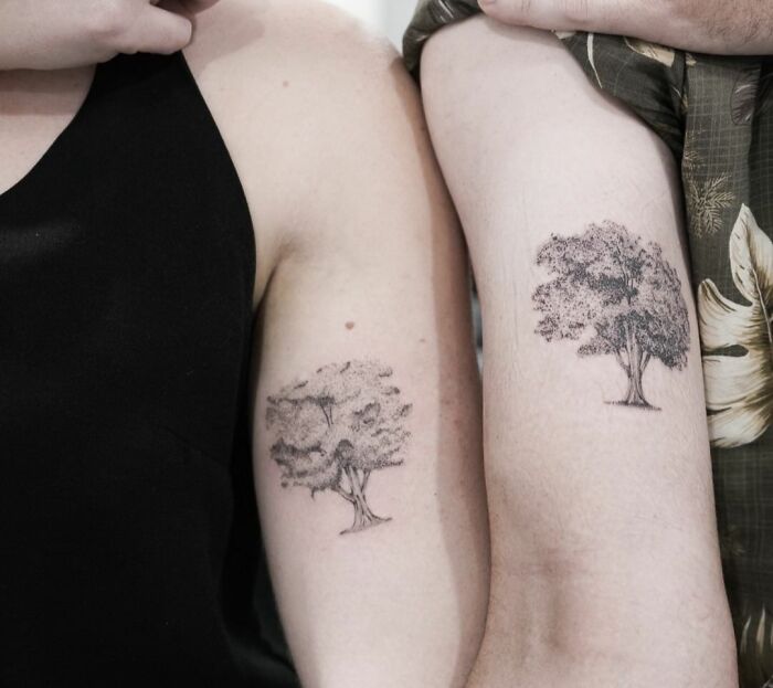 Matching tree tattoos on arms for couples or friends, symbolizing a special bond.