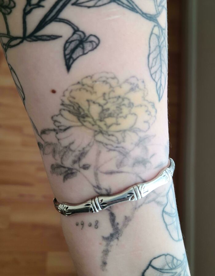 Floral tattoo seamlessly aligns with a silver bracelet, showcasing a perfect match with the situation.