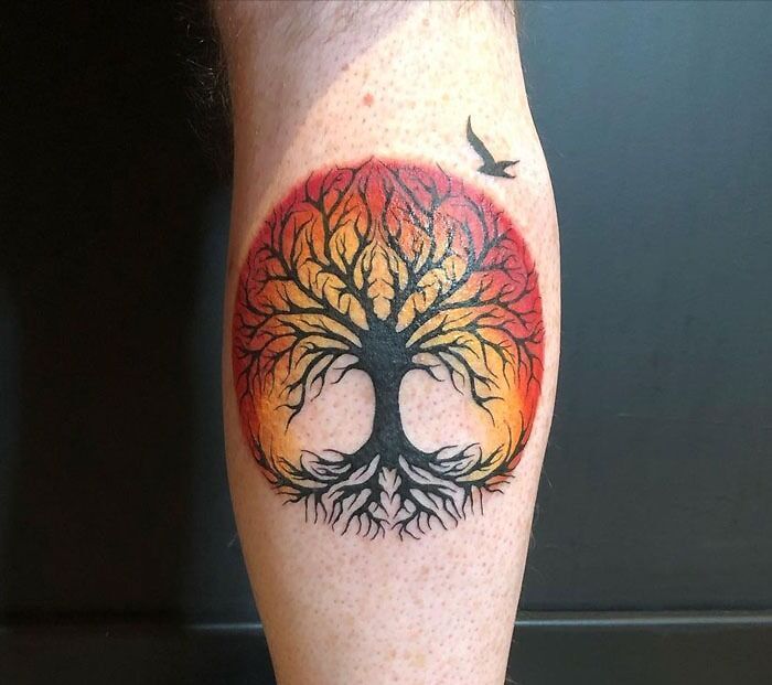 Colorful tree and bird calf tattoo design, showcasing unique calf tattoo ideas.
