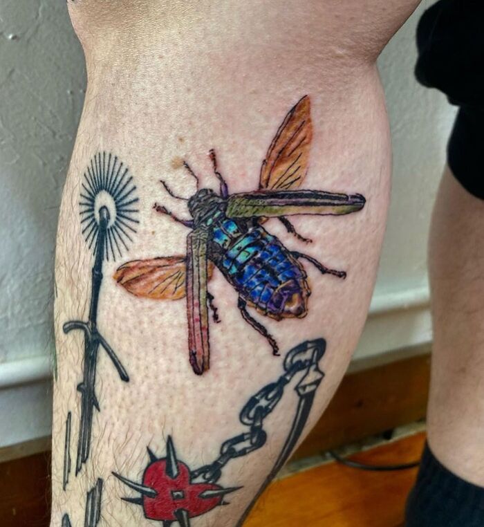 Colorful insect tattoo on calf with additional designs, showcasing unique calf tattoo ideas.