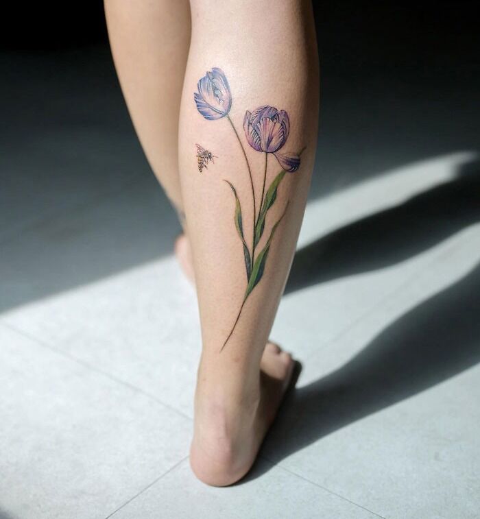 Calf tattoo featuring delicate purple flowers and a bee, showcasing unique ink art ideas.