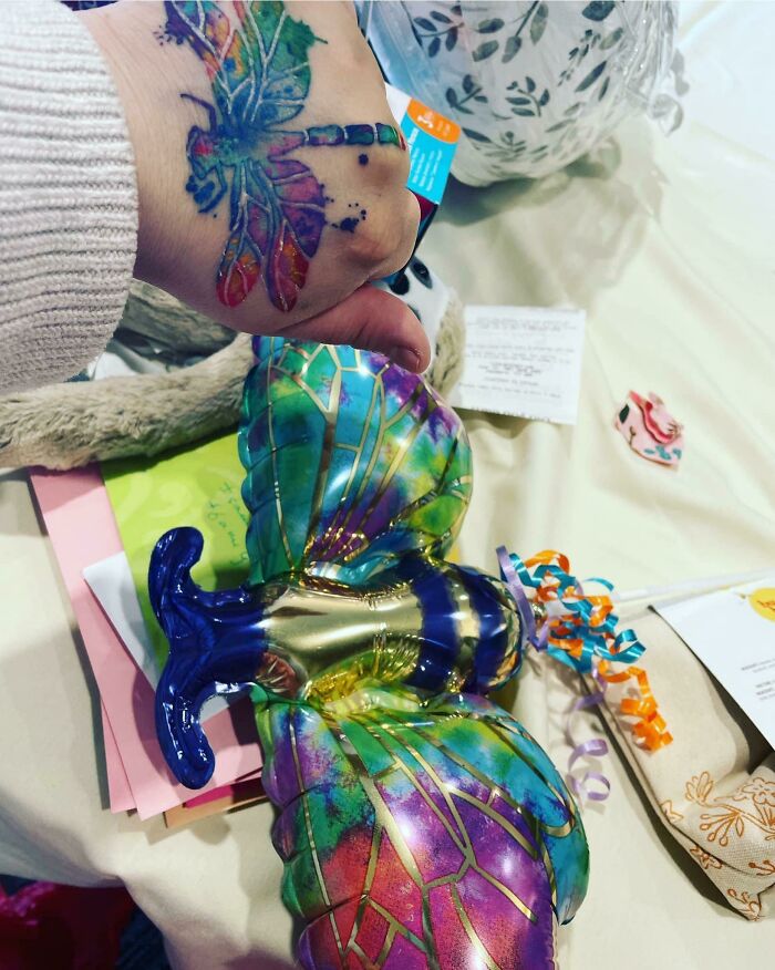 Colorful dragonfly tattoo matching perfectly with vibrant balloon on a table.