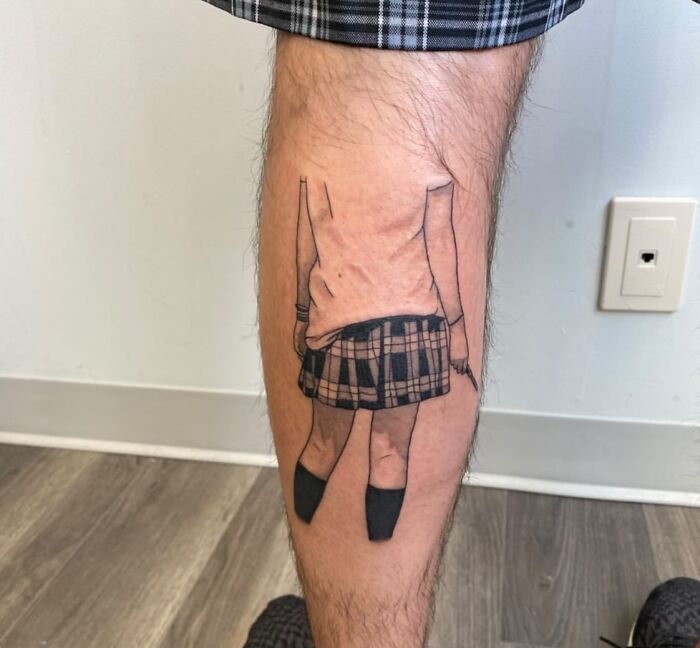 Calf tattoo featuring a minimalist design of a person in a plaid skirt and sweater, creating an optical illusion.