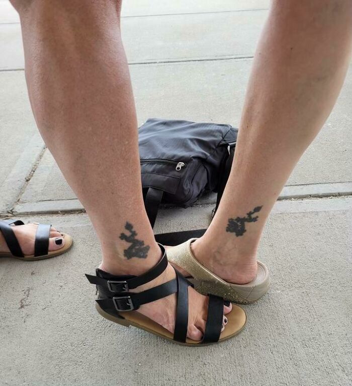 Two legs with matching tattoos side by side, both wearing sandals.