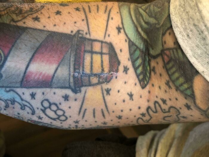 Lighthouse tattoo on arm aligns perfectly with scar, reflecting unexpected matching tattoos.