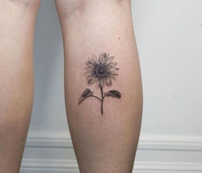 Sunflower calf tattoo showcasing coolness with detailed petals and leaves.