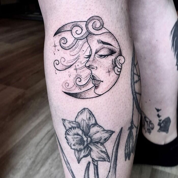 Calf tattoo featuring a stylized moon face and floral design, showcasing cool tattoo art on the leg.