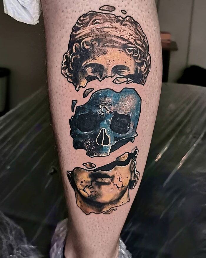 Calf tattoo featuring a segmented design with a skull and classical sculptures.