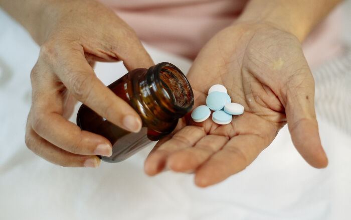 Hands taking out pills from brown medicine bottle